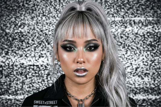Person with silver hair and dark makeup against a textured background